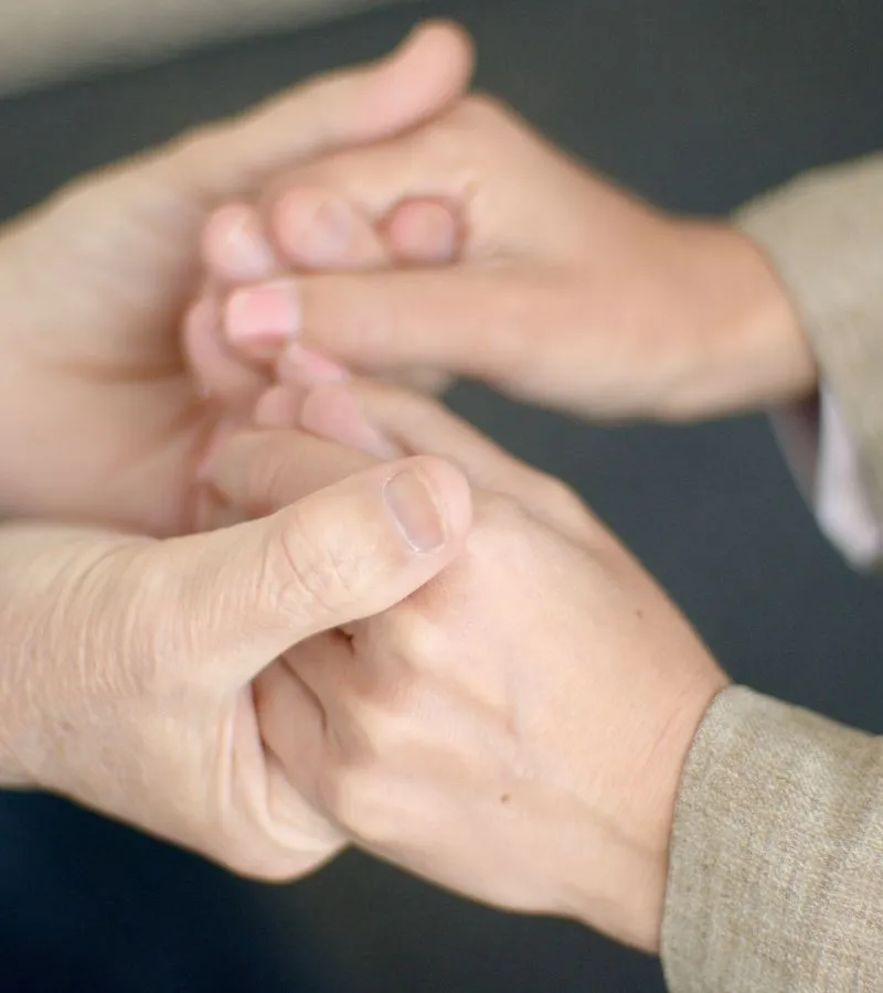 Two people clasping hands in a supportive gesture